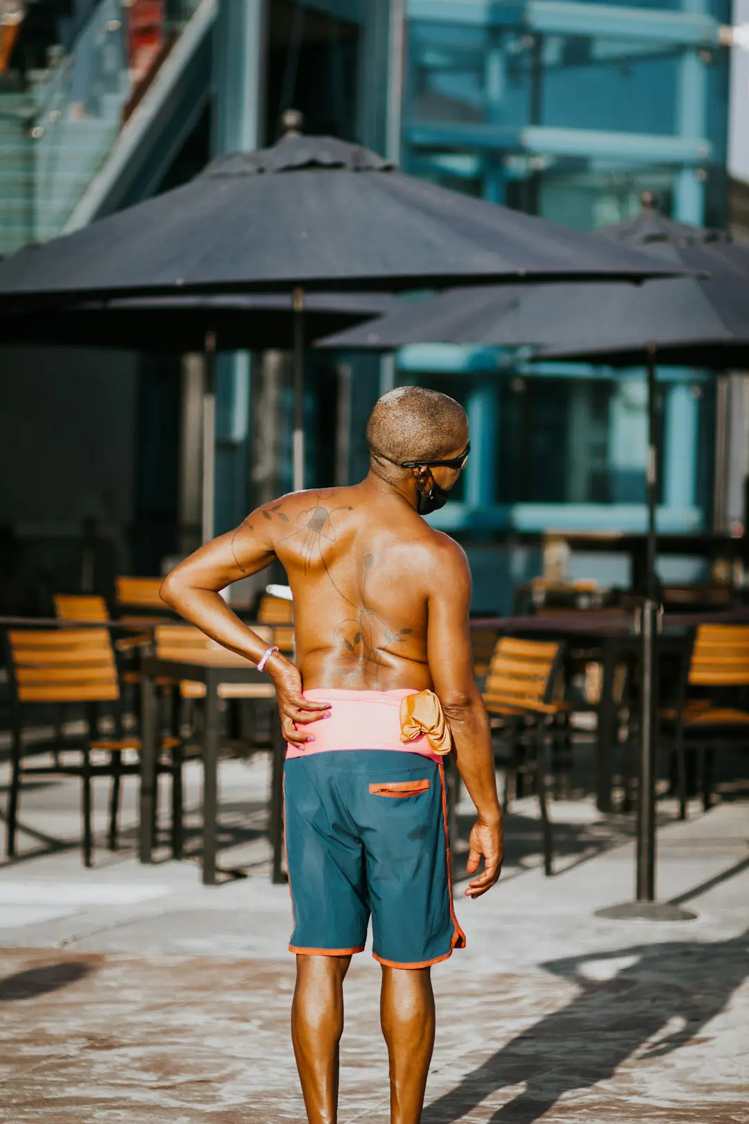 Photo by Gabe Pierce topless man in blue denim jeans standing near brown wooden table